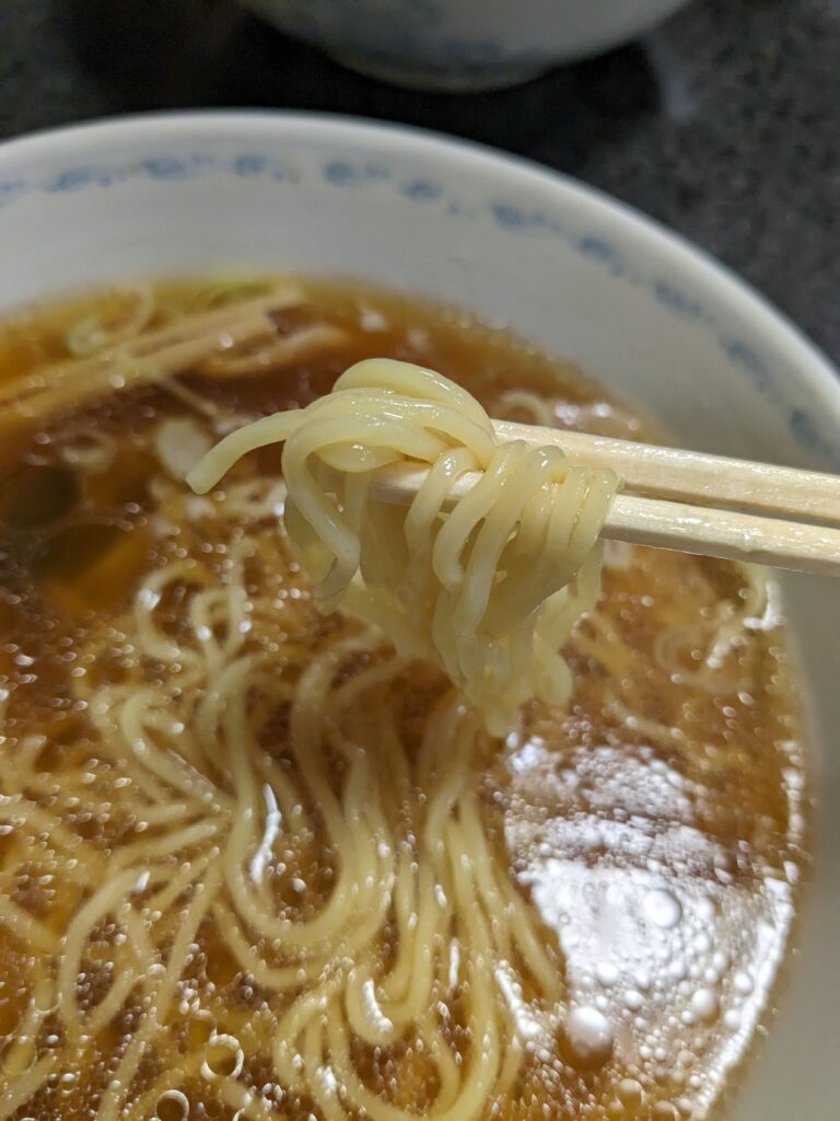 前田家の細ストレート麺を箸で持ち上げた様子。スープがしっかり絡む