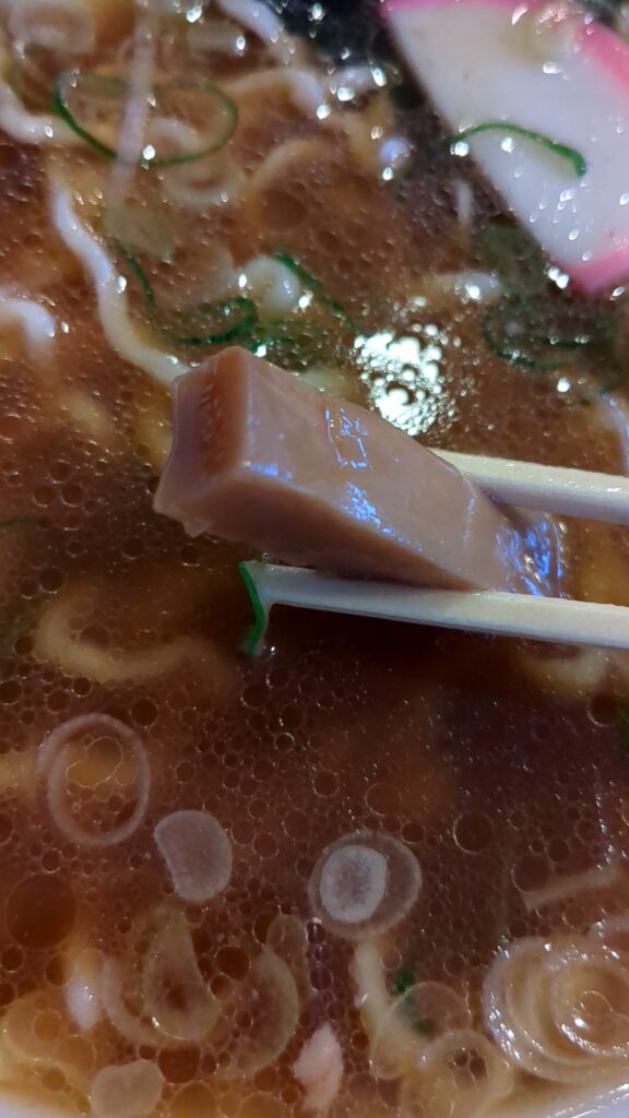 麺辰の中華そばにトッピングされた極太メンマのアップ。箸で持ち上げられている