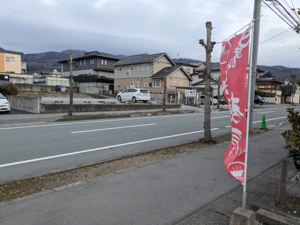 麺辰の店舗側から見た第二駐車場。道路を挟んで斜め向かいにある砂利の駐車スペース