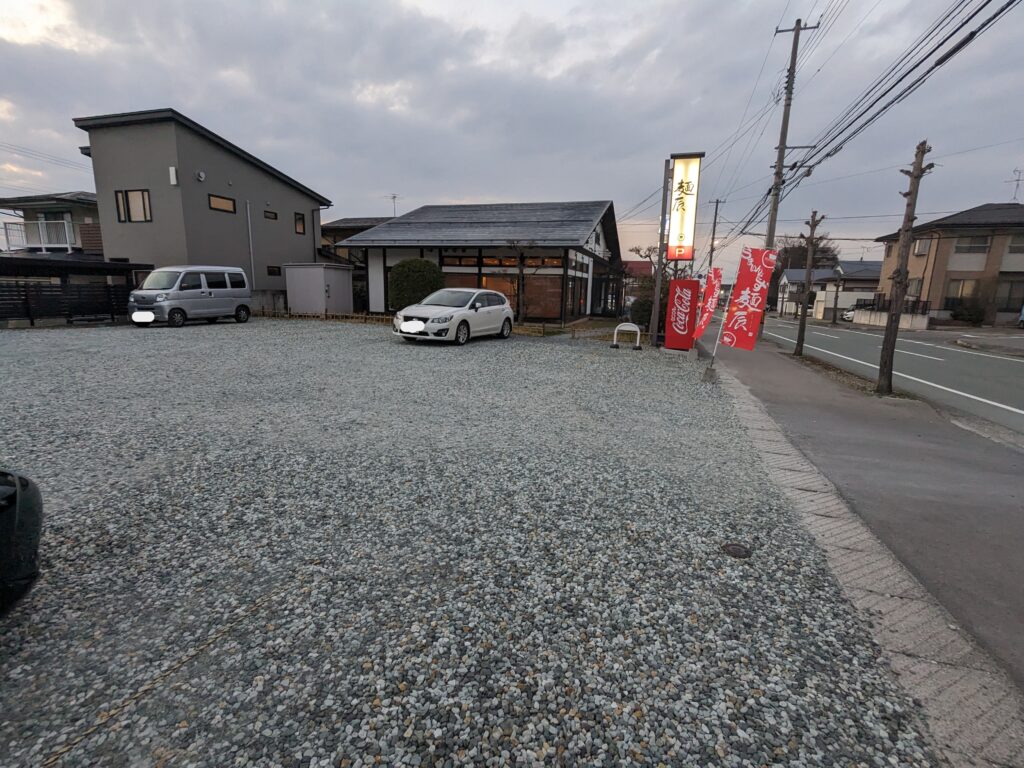 麺辰の店舗前にある広々とした第一駐車場。砂利敷きで10台以上駐車可能
