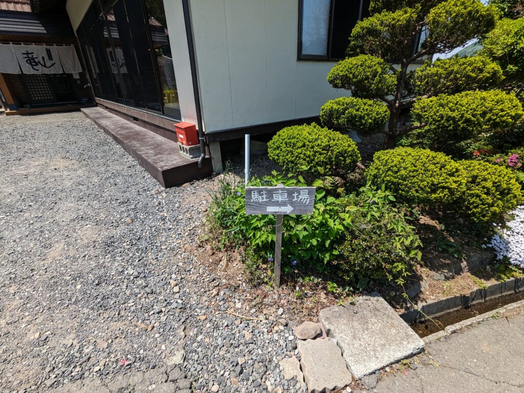 『手打そば竜山』の駐車場案内看板と店舗横のスペース