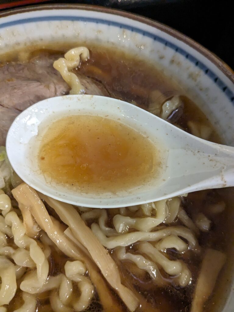 麺屋ほんわかの中華そばスープ。レンゲにすくった魚介だしの醤油スープ。
