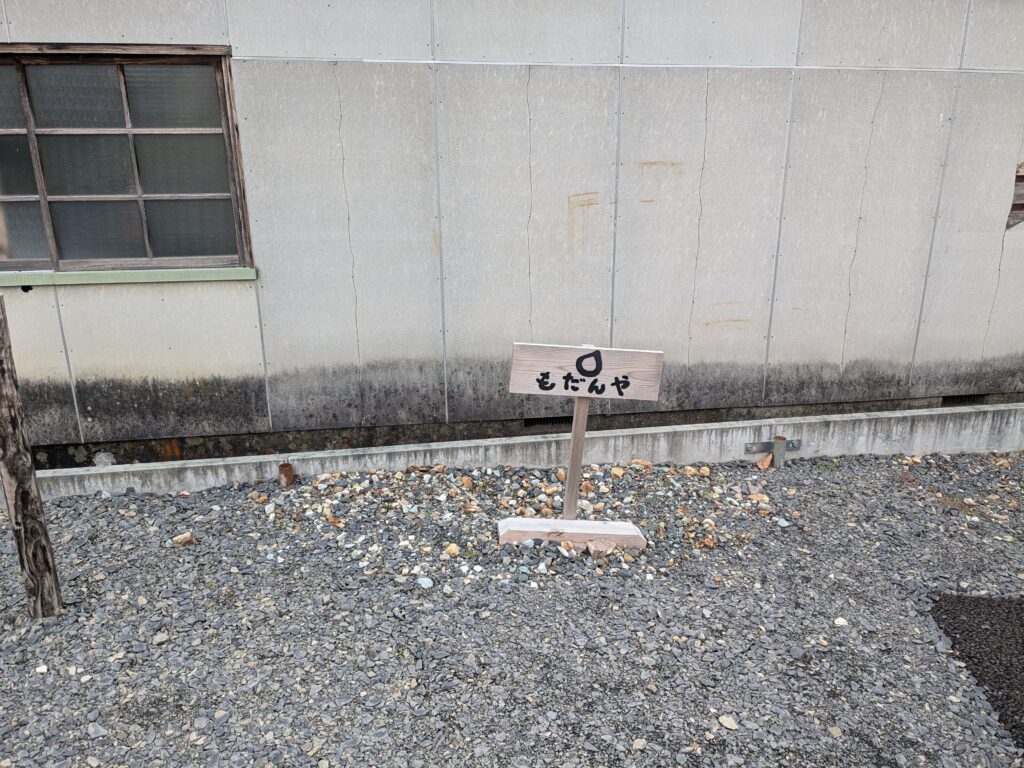 もだんやの駐車場を示す木製の看板