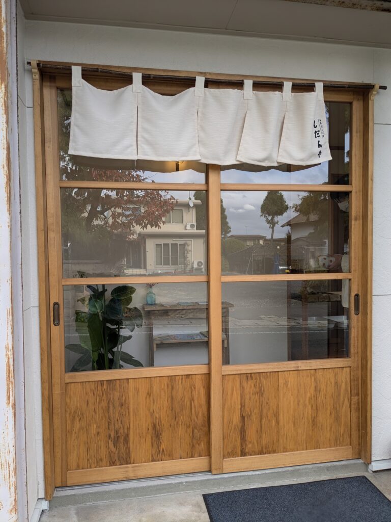 もだんやの木製引き戸と白いのれん