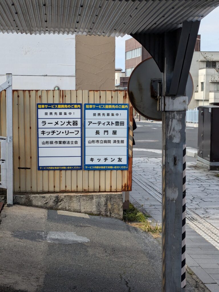 千足屋パーキングに掲示された提携先案内看板。「ラーメン大器」などが記載されている。