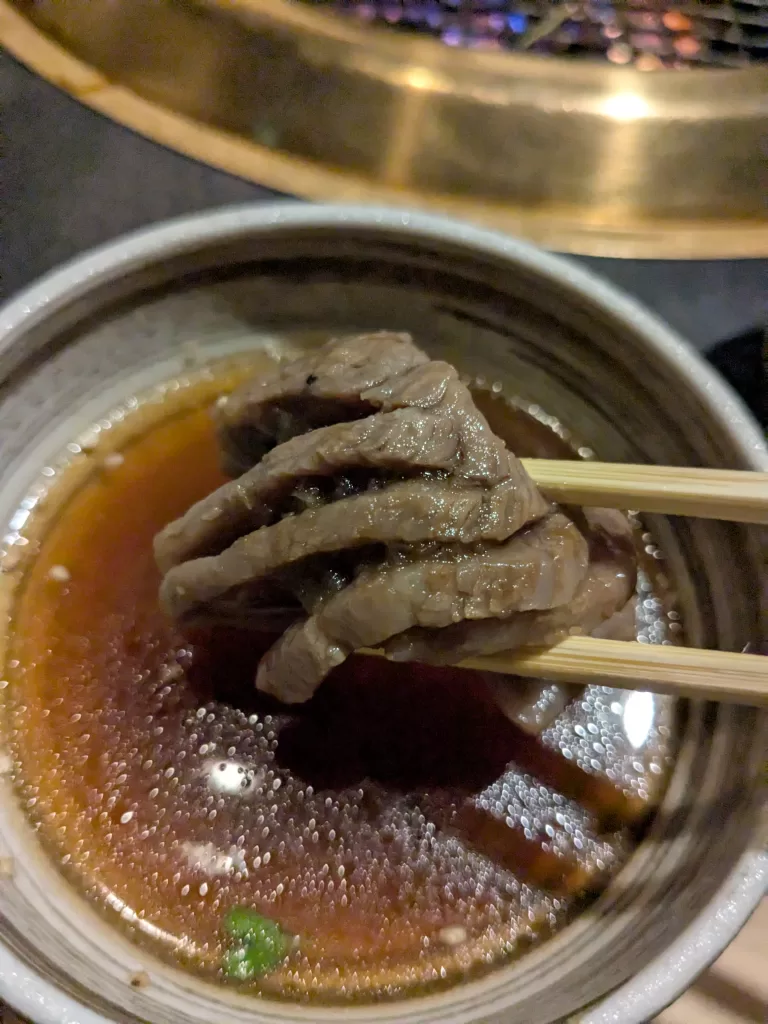 焼いた「もも肉みぞれ焼き」を洗いダレにつけて、箸で持ち上げている。